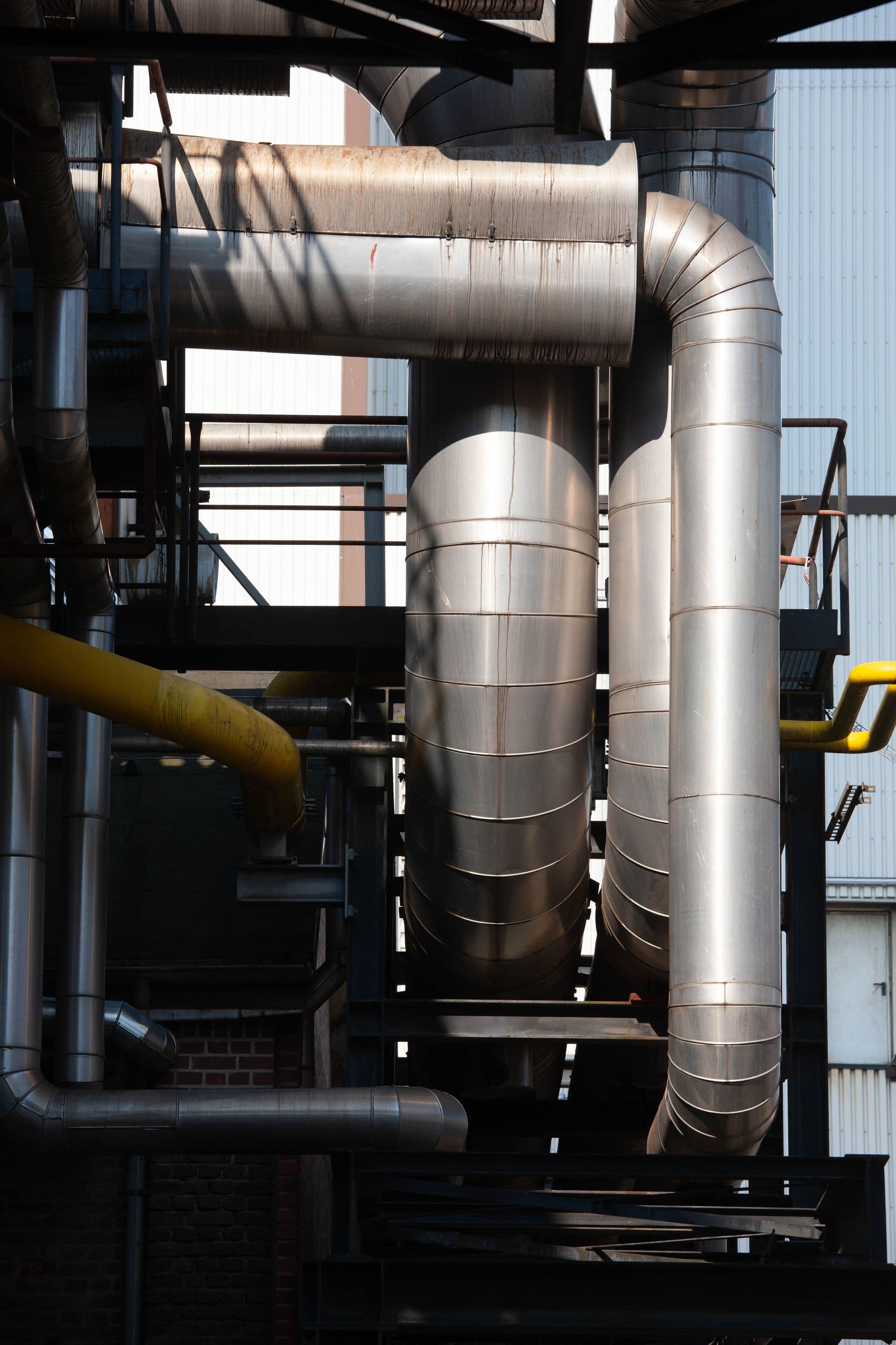 Cañería industrial de acero inoxidable con ramal de gas en planta